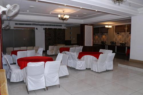 a room with white chairs and tables with red table cloth at Hotel Pushap Palace in Patiāla