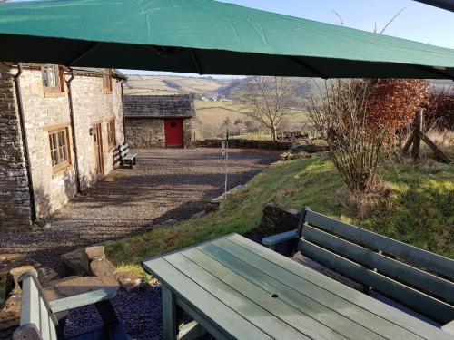 a wooden bench sitting under an umbrella next to a building at Eco Cottage Joe the Buck in Craven Arms