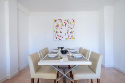 une table à manger avec des chaises blanches et un tableau dans l'établissement 2Br Apartment 100m from Beaches Terrace & Parking, à Cannes