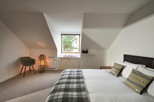 a bedroom with a bed and a window and a chair at Tanamuir, overlooking Loch Fyne, Strachur in Cairndow
