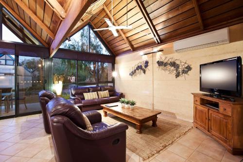 a living room with leather furniture and a flat screen tv at Whalers Cove Villas in Dunsborough