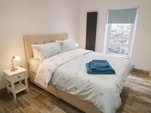 a bedroom with a bed with a blue towel on it at Old Shop Cottage in Limavady