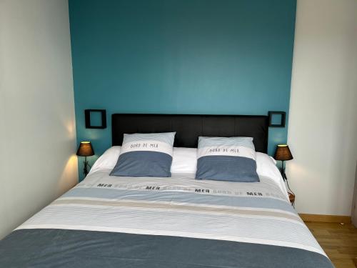 a blue bedroom with a bed with two pillows at La Rose des Mers in Tréffiagat