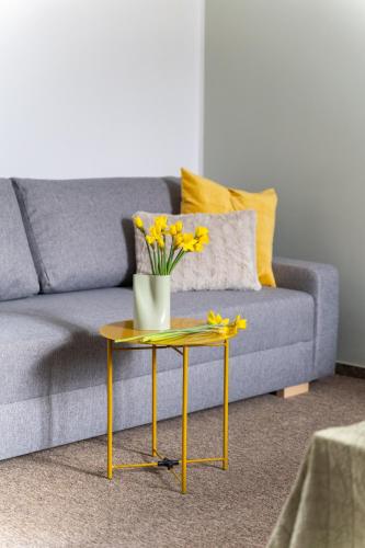a living room with a couch and a table with yellow flowers at Penzion Expo Dream #33 by Goodnite cz in Brno