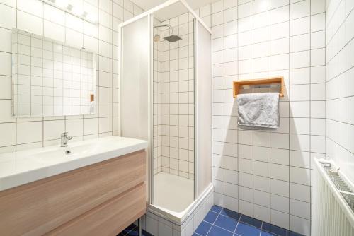 uma casa de banho em azulejos brancos com um lavatório e um chuveiro em The Old Town Lodge in the Heart of Antwerp em Antuérpia