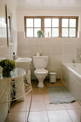 a bathroom with a toilet and a sink and a tub at Crompton Cottage in Henburg Park