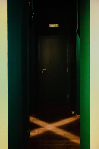 an open door into a dark room with a green door at GITADIN - Deluxe Suite Valens - Historical Center in Liège