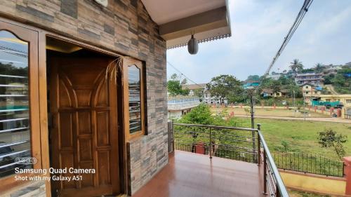a room with a balcony with a view of a field at Varam Homestay in Madikeri