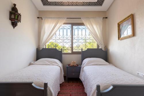 two twin beds in a bedroom with a window at Dar Ghita en campagne in O Ben Slimane