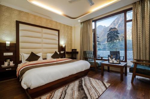 a bedroom with a large bed and a large window at Hukam's Holiday Home in Kasol