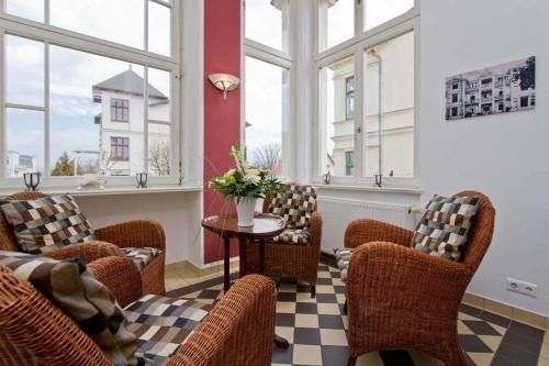 ein Wartezimmer mit Stühlen, einem Tisch und Fenstern in der Unterkunft Die Villa, App 1 in Ahlbeck