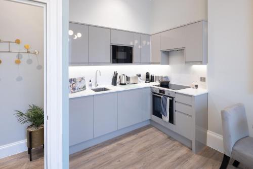 a kitchen with white cabinets and a sink at Redmayne House - Urban Apartments in Bristol