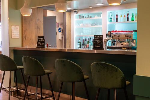 a bar with four chairs in front of a counter at ibis Dunkerque in Dunkerque