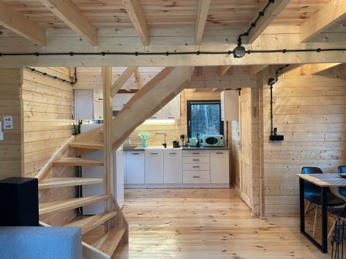 a kitchen with wooden walls and stairs in a house at Domek Na Winklu in Skrzynka