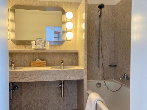 a bathroom with a sink and a shower with a mirror at Rössli Hurden in Hurden