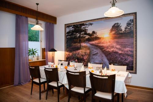 a dining room with a table and a large painting on the wall at Landgasthof Heidetal in Betzendorf