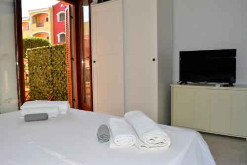 1 dormitorio con 1 cama con 2 toallas y TV en Appartamenti Residence Poseidone en Santa Teresa Gallura