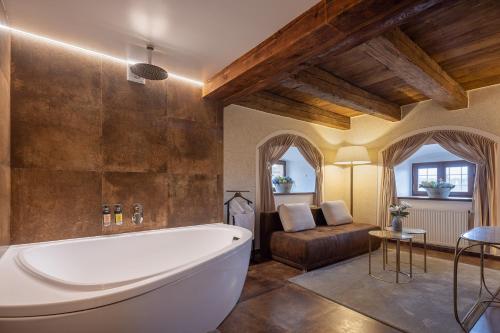 a large bathroom with a tub and a couch at Pytloun Chateau Hotel Ctěnice in Prague
