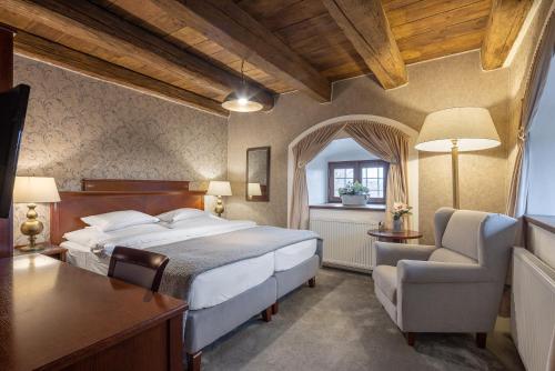 a bedroom with a bed and a desk and a chair at Pytloun Chateau Hotel Ctěnice in Prague