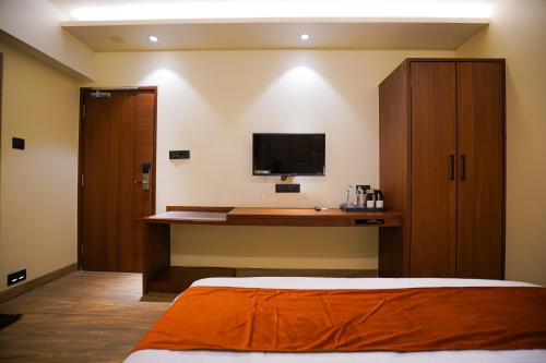 a bedroom with a bed and a desk with a television at Hotel El Magnifico in Surat