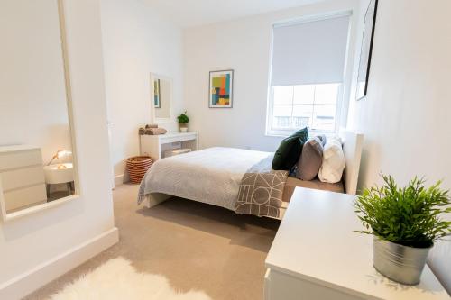 a white bedroom with a bed and a window at Modern and Spacious 1 Bed Apartment City Centre in Norwich