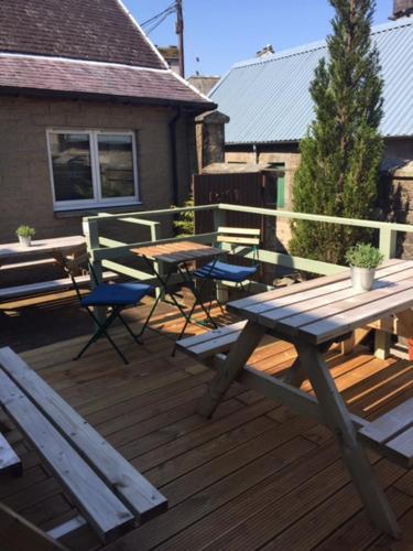 a wooden deck with a picnic table and chairs at Eskdale Hotel in Langholm
