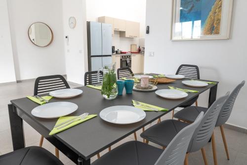 a dining room table with chairs and a black table with plates at Achziv Sea&Sun in Nahariyya
