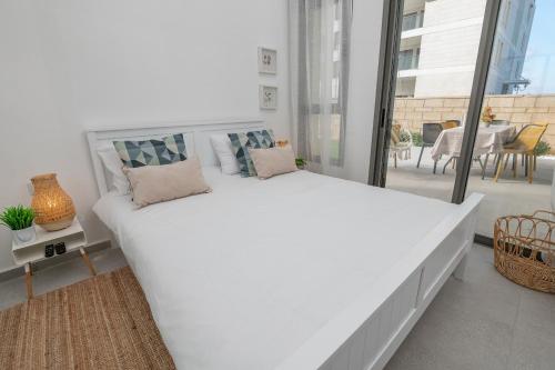 a large white bed in a room with a balcony at Achziv Sea&Sun in Nahariyya