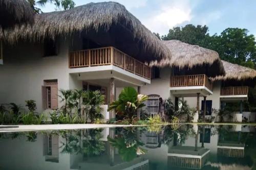 uma casa com telhado de palha e uma piscina em Halcyon Mawella em Tangalle