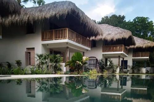 a house with a thatched roof and a swimming pool at Halcyon Mawella in Tangalle