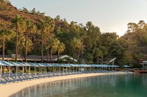 a beach with chairs and umbrellas next to the water at D Maris Bay in Hisarönü