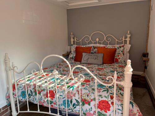 1 dormitorio con cama blanca y colcha de flores en The Lodge, en Little Clacton
