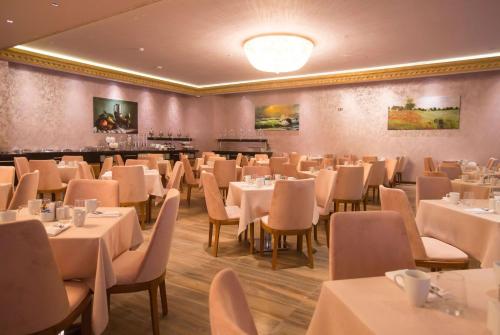 فندق ويندهام باتومي في باتومي: غرفة طعام مع طاولات وكراسي بيضاء