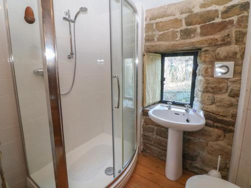 a bathroom with a glass shower and a sink at Wyndell Cruck Cottage in Sheffield