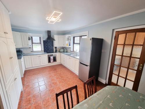 a kitchen with a refrigerator and a table and chairs at 3 Bed Renovated Cottage Carramore Lake, Belmullet in Ballina