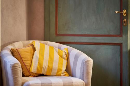 a white chair with two yellow and white pillows at Alla Scala 1746 in Siena