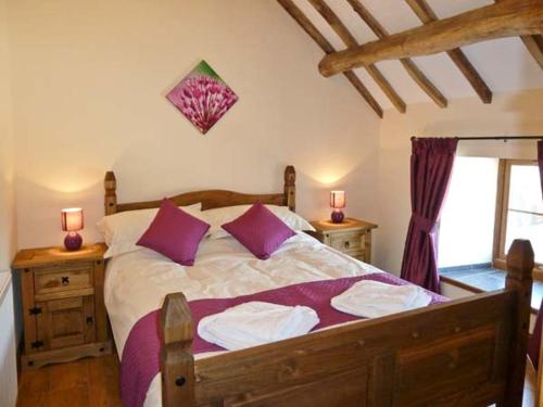 ein Schlafzimmer mit einem großen Bett mit lila Kissen in der Unterkunft Beudy Bach in Abergele