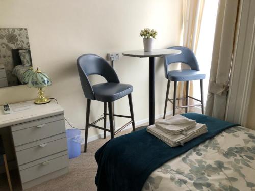 a bedroom with a bed and two chairs and a table at Bella Vista Hotel in Weston-super-Mare