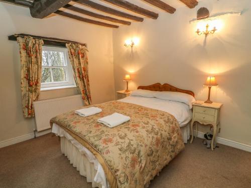 a bedroom with a bed with two towels on it at Beckside Cottage in Mansergh