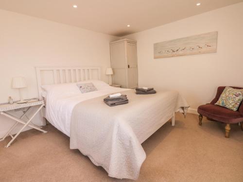 a bedroom with a white bed and a chair at Searles in Lympstone