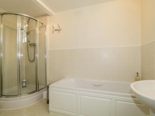 a white bathroom with a shower and a sink at Carpenters Cottage in Cockermouth