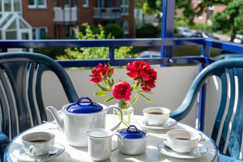 a table with cups and a vase with flowers on it at K & R Appartements Binz in Binz