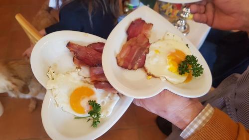 a person holding two plates of eggs and bacon at FerienAppartments Landhaus FühlDichWohl in Fehring