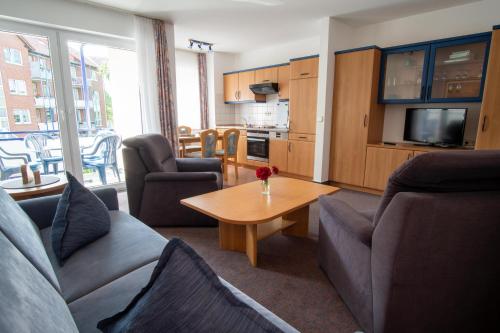 ein Wohnzimmer mit Sofas und einem Tisch sowie eine Küche in der Unterkunft K & R Appartements Binz in Binz