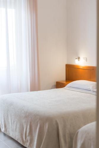 a bedroom with a white bed and a window at Hotel Viola in Gaeta