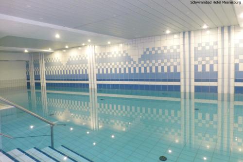 a large swimming pool with blue water in a building at Hotel Meeresburg in Norderney