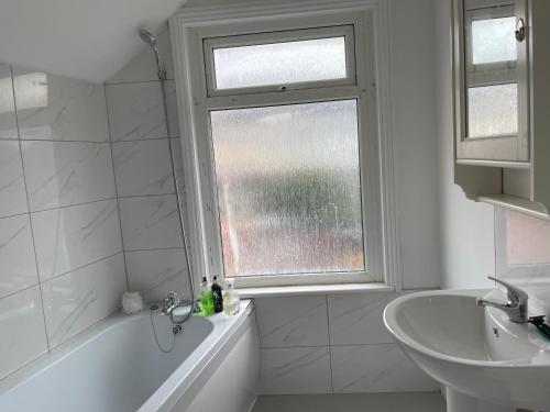 a bathroom with a tub and a sink and a window at Poplar street Contractors & Leisure by Leecroft Stays in Wellingborough