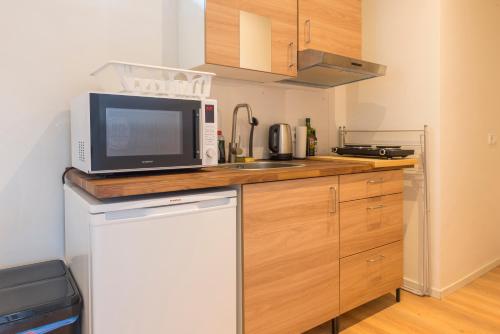 uma pequena cozinha com um micro-ondas e um lavatório em Left Garden Suite in Villa near Centre and TUe em Eindhoven
