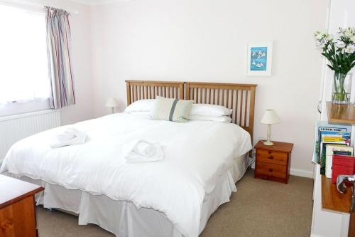 ein Schlafzimmer mit einem großen weißen Bett mit Handtüchern darauf in der Unterkunft 15 Churchfields - Bungalow with Estuary Views and Parking in Dartmouth