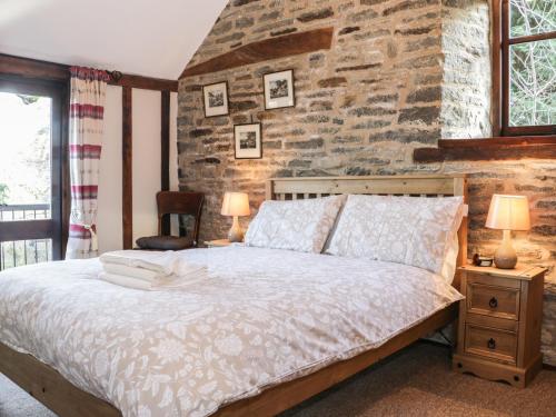 a bedroom with a bed and a stone wall at The Granary in Bucknell